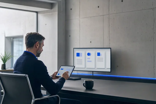 A manager approving items on a tablet at a desk in a minimal office